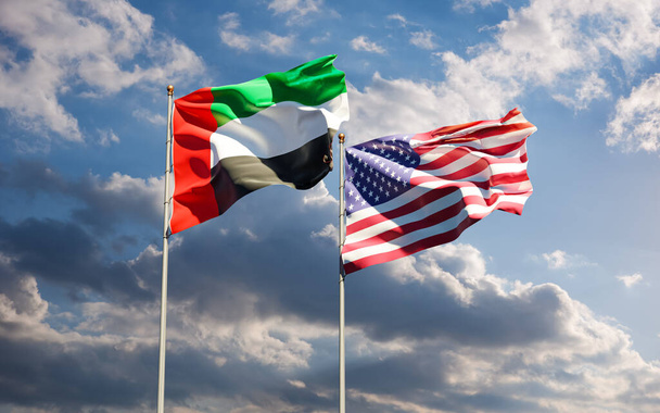 Flaggen der USA und der Vereinigten Arabischen Emirate vor dem Hintergrund des Himmels. Symbol der internationalen Beziehungen zwischen den Vereinigten Staaten von Amerika und den Vereinigten Arabischen Emiraten. - Foto, Bild