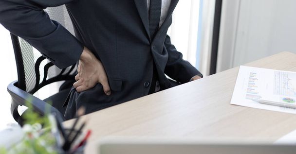 Asiatische Mann Mitarbeiter ruht nach ihrer harten Arbeit und Überstunden spät im Büro, Entspannung der Körpermüdigkeit, Handgelenkschmerzen. - Foto, Bild