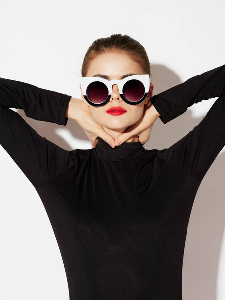 A woman in a black turtleneck and fashionable glasses touches her neck  - Photo, Image