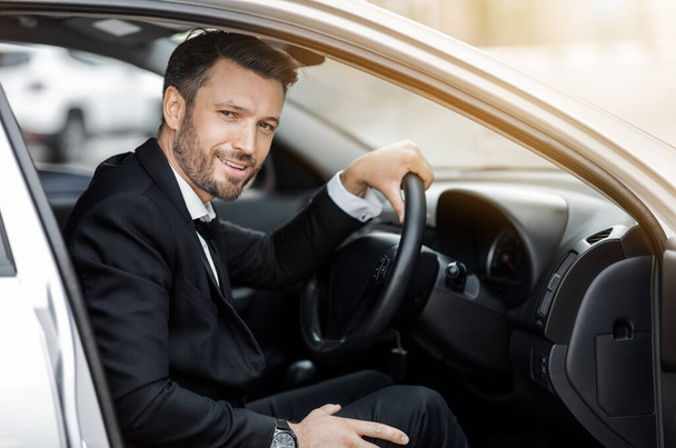 Feliz joven empresario sentado en coche, conduciendo al aeropuerto - Foto, imagen