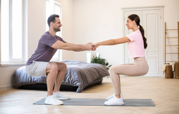 Mann und Frau üben Händchenhalten, gemeinsames Training zu Hause - Foto, Bild