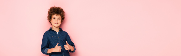 panoramic crop of joyful and curly boy showing thumbs up isolated on pink  - Foto, Bild