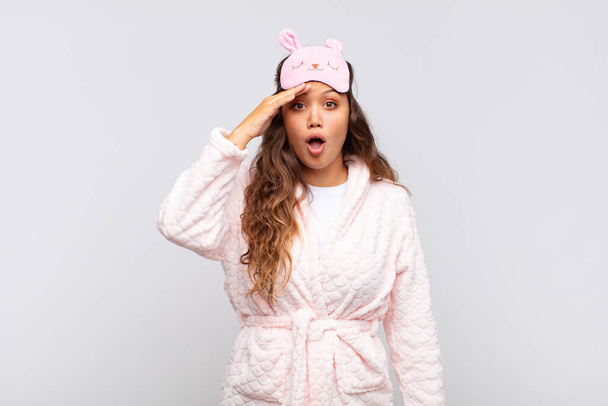 young pretty woman looking happy, astonished and surprised, smiling and realizing amazing and incredible good news wearing pajama - Photo, image