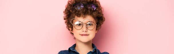 panoramic shot of curly boy in bunch of eyeglasses looking at camera on pink   - Photo, Image