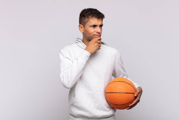 young man thinking, feeling doubtful and confused, with different options, wondering which decision to make. basket concept - Фото, изображение