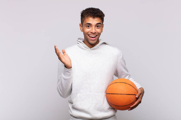 young man feeling happy, surprised and cheerful, smiling with positive attitude, realizing a solution or idea. basket concept - Фото, изображение