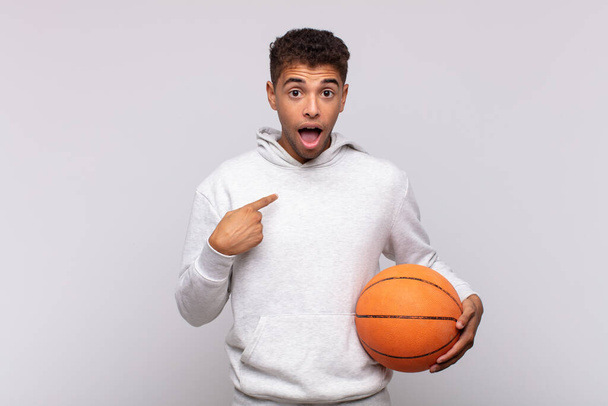 young man looking shocked and surprised with mouth wide open, pointing to self. basket concept - Fotoğraf, Görsel