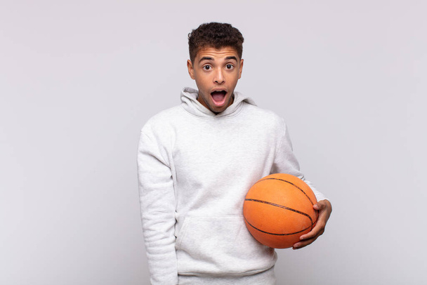 young man looking very shocked or surprised, staring with open mouth saying wow. basket concept - Foto, Bild