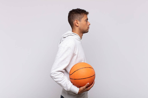 young man on profile view looking to copy space ahead, thinking, imagining or daydreaming. basket concept - 写真・画像