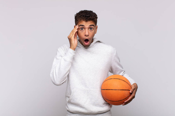 young man looking surprised, open-mouthed, shocked, realizing a new thought, idea or concept. basket concept - Photo, Image