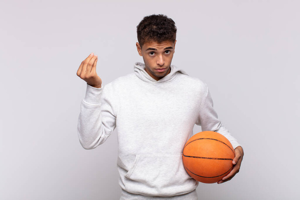 young man making capice or money gesture, telling you to pay your debts!. basket concept - Foto, imagen