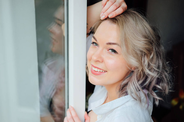 Mujer en su piso vistiéndose cerca del marco de la ventana. Estilo francés. Peinado colorido moderno. - Foto, Imagen