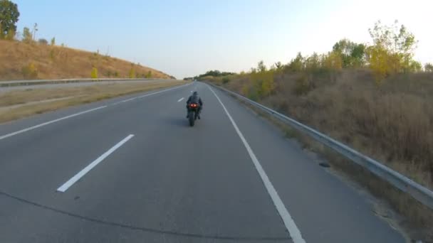 Suivez à vélo sur la moto sport moderne à l'autoroute d'automne. Motocycliste course sa moto sur la route de campagne. Homme conduisant un vélo pendant le voyage. Concept de liberté et d'aventure. Plan aérien - Séquence, vidéo