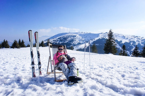 Giovane donna che riposa e beve tè da un thermos dopo aver sciato sulla pista da sci in una giornata di sole. Ragazza sorridente con sci alpino. Pista da sci Kopaonik - Foto, immagini