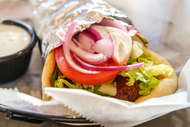 Fresh and healthy falafel with tzatziki tomato red onion and iceberg lettuce in pita bread - Photo, Image