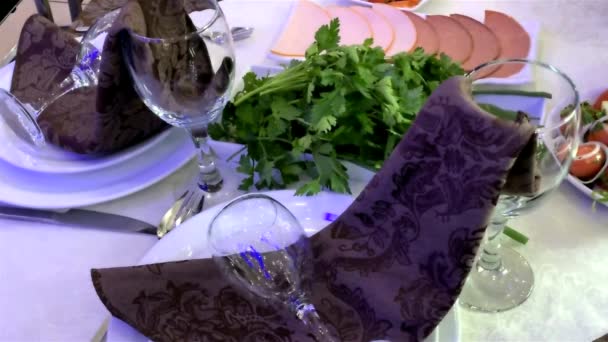 Geserveerde feestelijke tafel. Wit tafelkleed, bruin servet, witte borden, wijnglazen, bestek - Video