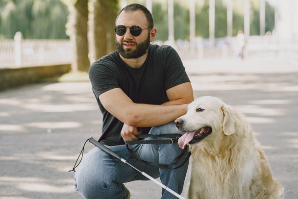 Blind man with guide dog in a summer city - Fotó, kép
