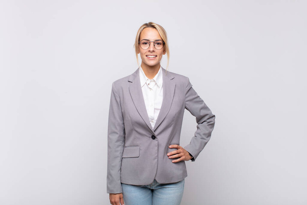 young businesswoman smiling happily with a hand on hip and confident, positive, proud and friendly attitude - Zdjęcie, obraz