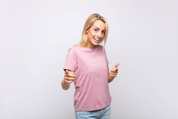 Woman smiling with a positive, successful, happy attitude pointing to the camera, making gun sign with hands - Foto, imagen