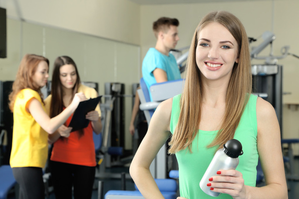 Young womans engaged in simulator in gym - Foto, afbeelding