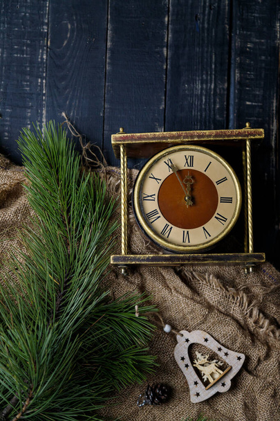 Kultainen vintage kello, mänty oksat ja puinen lelu bell mustalla taustalla. Hyvää joulua, uudenvuodenaattona ja talvilomien käsite. Minuutista keskiyöhön. Huippunäkymä, paikka tekstille. Pystysuora laukaus - Valokuva, kuva
