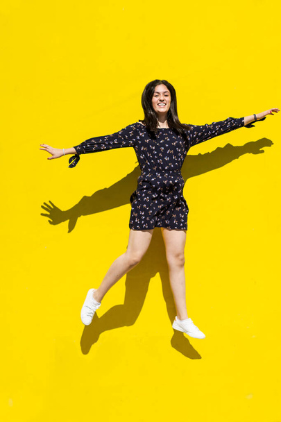 Urban women latin jumping over isolated yellow background and dancing - Photo, Image