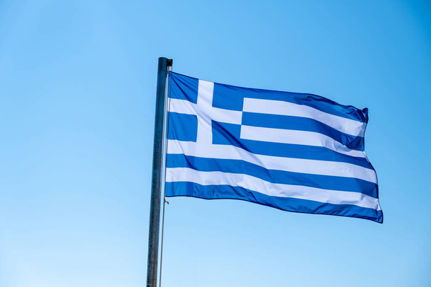 Griekenland teken symbool. Griekse vlag op vlaggenmast wapperend in de wind. Blauwe lucht, zonnige lentedag in Athene. - Foto, afbeelding