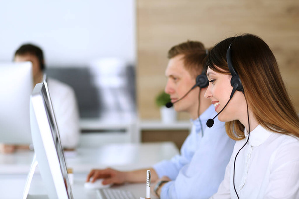 Call center. Group of diverse operators at work. Focus on beautiful asian woman in headset at customer service office. Business concept - Fotó, kép