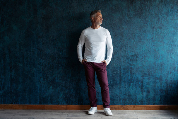 Casual Grey-haired Mature handsome man portrait over dark blue wall background. - Photo, image