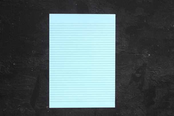 Colocación plana, vista superior, lámina azul y lápiz sobre un fondo de textura gris. Rayos de luz desde el lado - Foto, Imagen