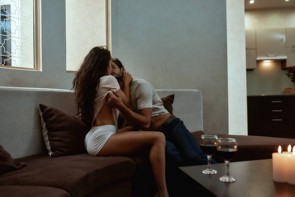 Seduce me. Young sexy man and woman are kissing before having sex on the couch - Foto, afbeelding