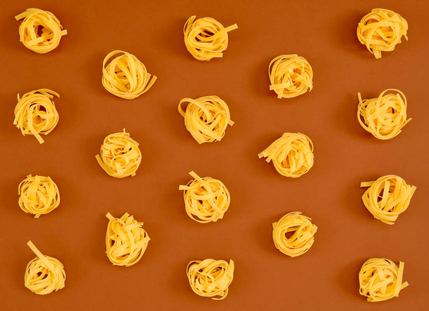 Image of a group of raw noodles placed on a brown cardboard background and captured from above - Фото, зображення