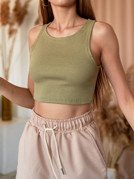 Mädchen trägt khakifarbenes Top. Sommeroutfit auf sportlichem Damenmodell - Foto, Bild