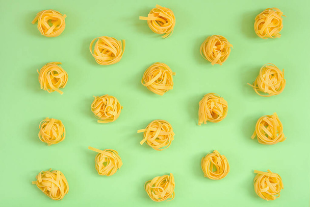 Image of a group of raw noodles placed on a green cardboard background and captured from above - Valokuva, kuva
