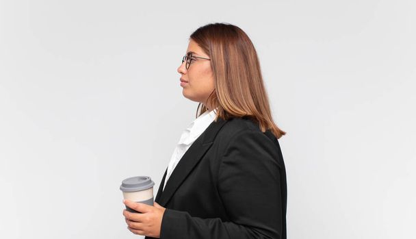 young businesswoman with a coffee on profile view looking to copy space ahead, thinking, imagining or daydreaming - Fotografie, Obrázek