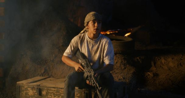 Teenager with rifle sitting in trench - Foto, Imagem