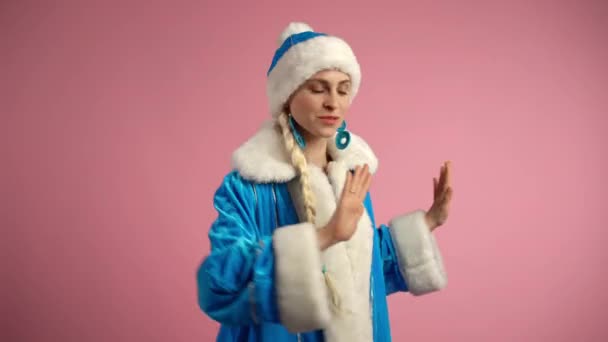 Wesoła Śnieżka w niebieskim zimowym kostiumie i z niesamowitym długim białym warkoczem tańczącym na odizolowanym różowym tle, podekscytowana uśmiechnięta kobieta gestykulująca rękami i pokazująca szczere emocje. Szczęśliwy Śnieg - Materiał filmowy, wideo