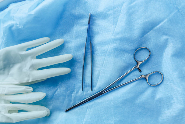 surgical instruments scissors and tweezers with gloves on a blue background. - Fotografie, Obrázek