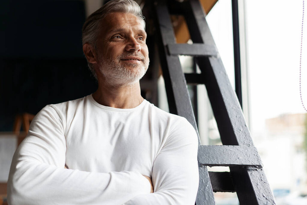 Business lifestyle. Casual Grey-haired Mature professional handsome businessman standing near window in his office - Foto, imagen