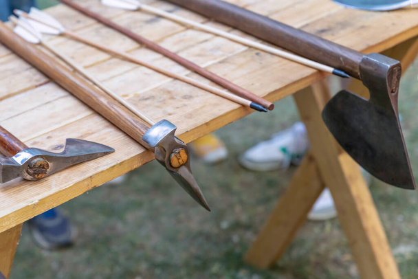 diverse strijdbijl en pijl wapen geplaatst op een houten tafel - Foto, afbeelding