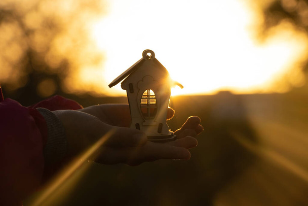 手は日没時の太陽を背景に小さな木の家を持ち夢の家 - 写真・画像