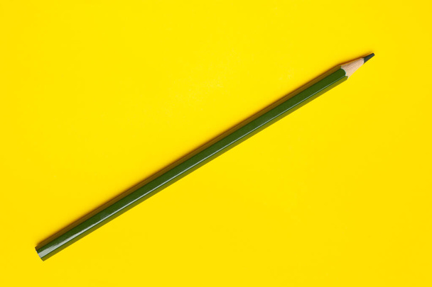 diagonal dark green sharp wooden pencil on a bright yellow background, isolated, copy space, mock up - Foto, Imagem