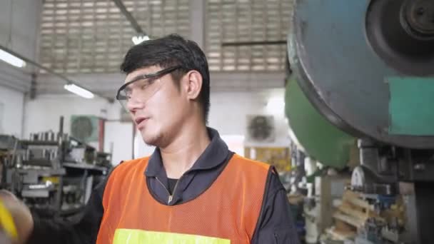 Ázsiai mérnök fáradt vegye le sisak és biztonsági szemüveg pihenni. Csapatszünet biztonsági egyenruhával fémlemez gyári gyártásban. Dolly kamera oldalnézete - Felvétel, videó