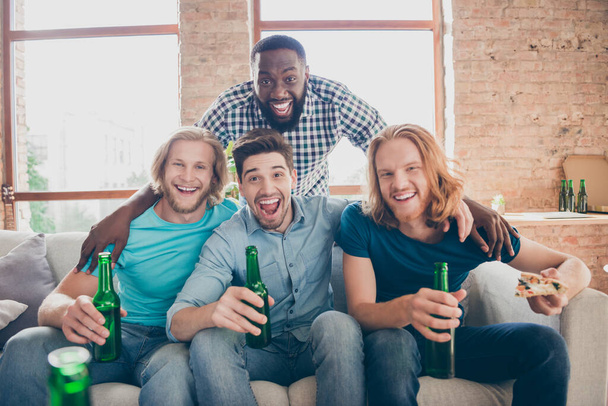 Four people best buddies men sit couch hold pint beverage bottle enjoy free time watching film movie hold pizza slice in house indoors - Foto, Bild