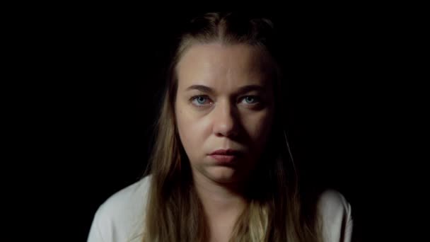 Απομονωμένο πορτραίτο μιας σοβαρής νεαρής γυναίκας σε μαύρο φόντο - Πλάνα, βίντεο