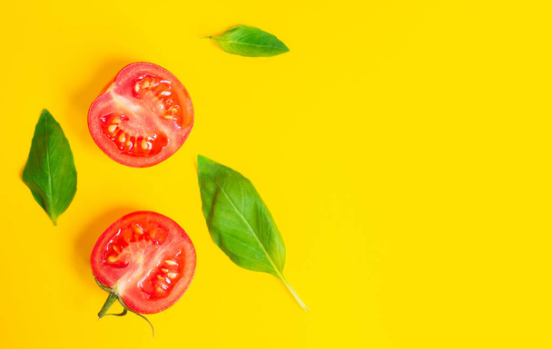 Healthy food and dieting concept. Red cherry tomatoes and oregano leaves isolated on yellow color studio background with copy space. Flat lay, view from top. - Фото, зображення
