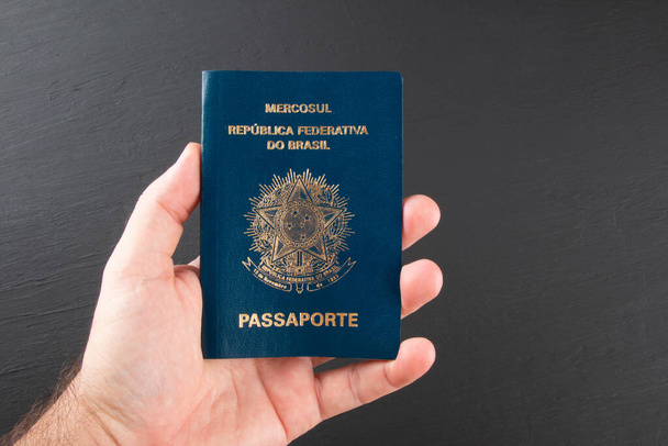 Hand holding Brazilian passport with black background - Photo, Image