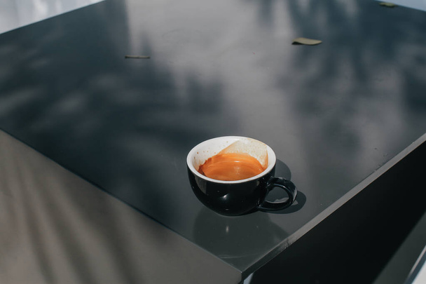 Kaffeetasse auf schwarzem Tisch mit Sonnenlicht im Garten an einem Sommermorgen, einem Ort zum Arbeiten. Grund zum Wecken. - Foto, Bild