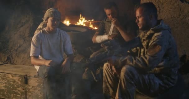 Soldaat toont pistool aan etnische tiener in de buurt van kampvuur - Video