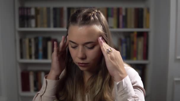 Retrato de una mujer estresada que tiene un terrible dolor de cabeza fuerte y masajea sus sienes - Imágenes, Vídeo